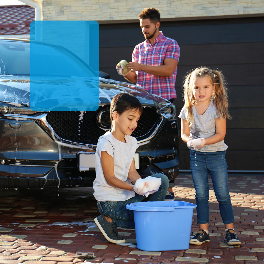 Young family washing car in front of home.